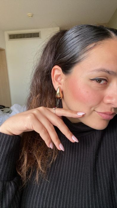A reviewer showcasing the earrings in a stylish look.