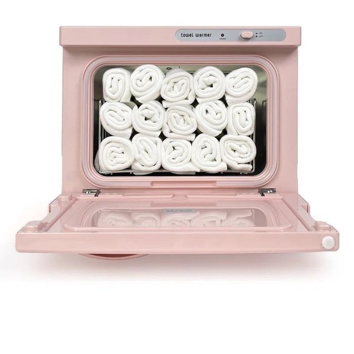 An open towel warmer with neatly stacked rolled towels neatly organized inside.