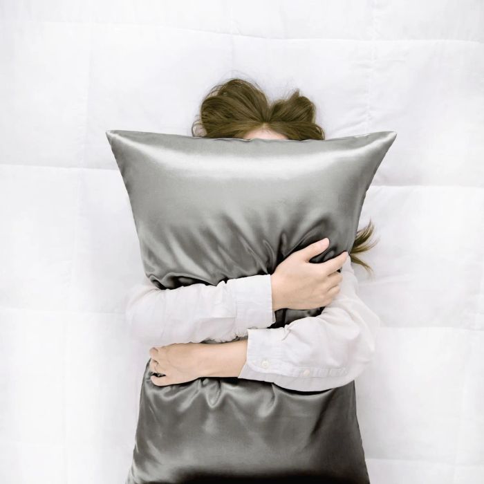 A model holding a sleek grey satin pillow.