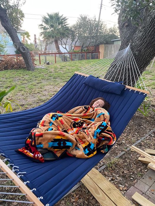 A reviewer is seen enjoying a nap in their blue hammock