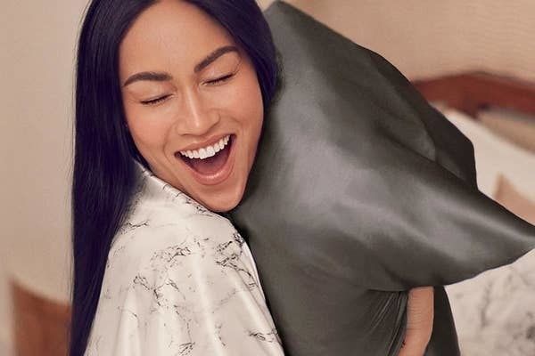 Model cuddling a pillow featuring the black silk pillowcase