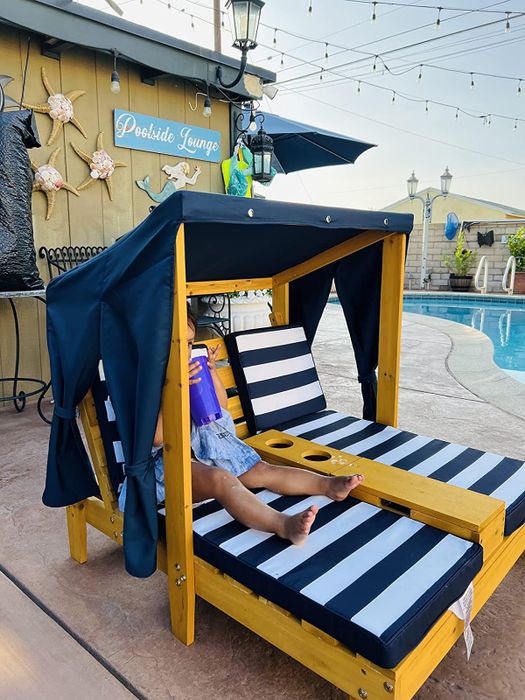 A person relaxing in a cabana-style poolside chair equipped with drink holders