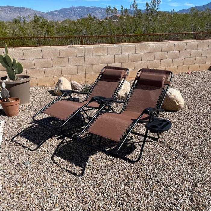 Two lounge chairs placed in a backyard with a desert landscape in the background, highlighting outdoor furniture