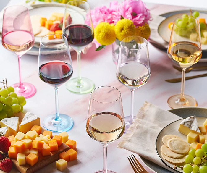 Six stemmed wine glasses in soft, translucent pastel hues