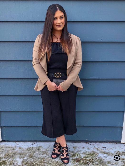 A reviewer showcasing the black belt, styled with a sleek black jumpsuit and a tan blazer.