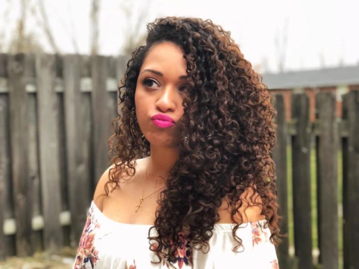 A reviewer showing off long, shiny, and well-defined curls
