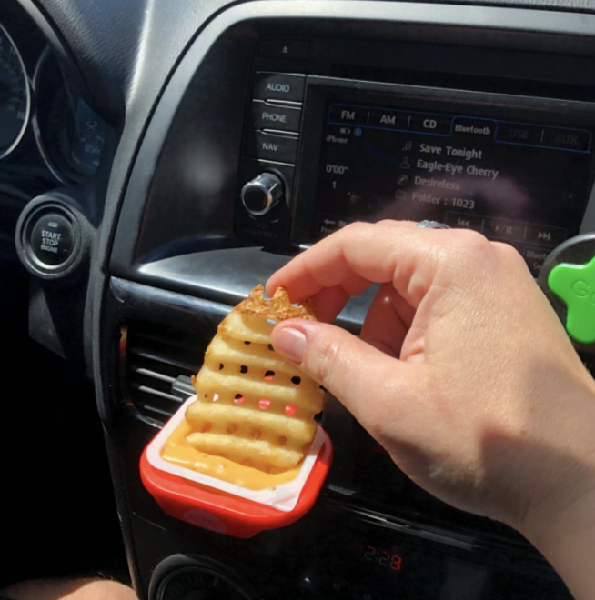 A reviewer dipping a crispy waffle fry into sauce held by the clip