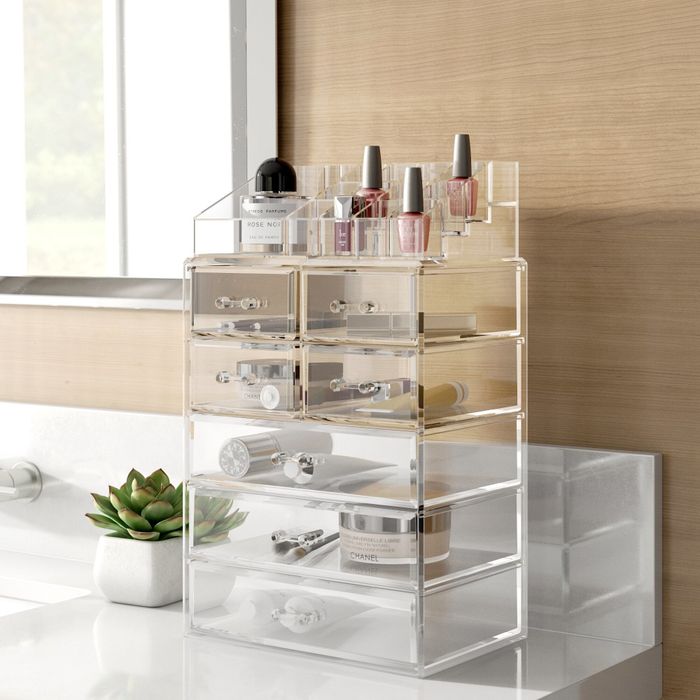 A clear makeup organizer in the bathroom, filled with brushes, lipsticks, creams, and other essentials.
