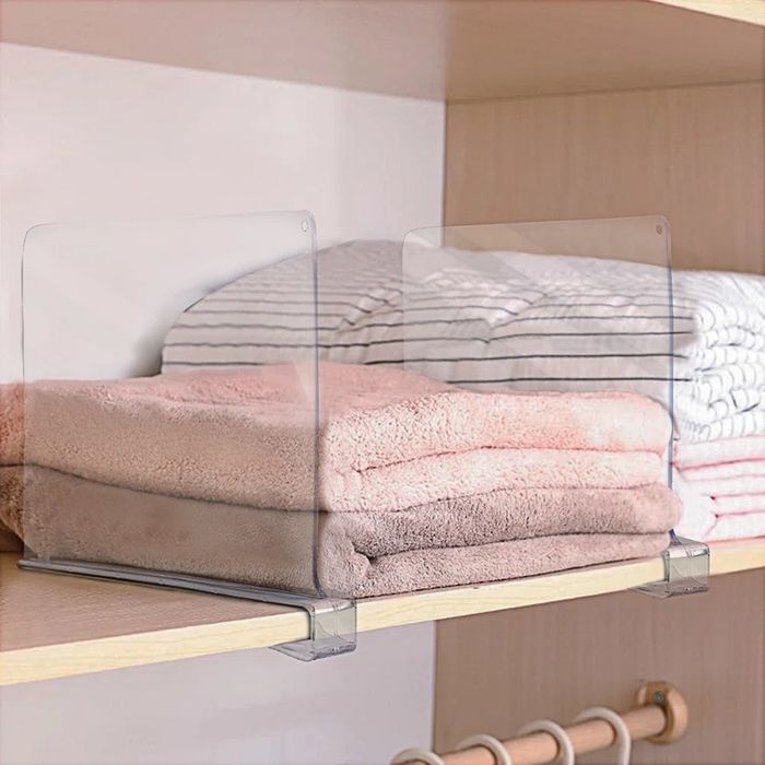 Two neatly folded towels on a wooden shelf, separated by clear acrylic shelf dividers