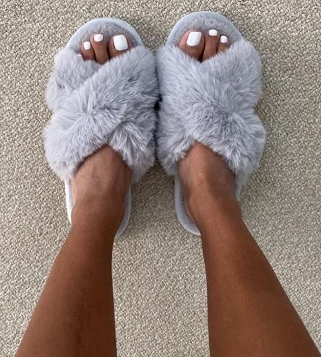 A reviewer wearing the cozy gray fuzzy slippers
