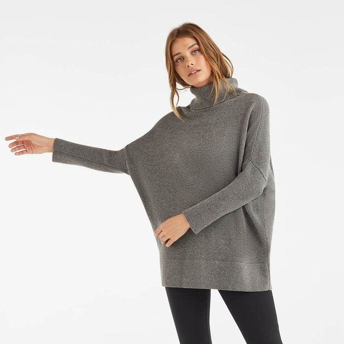 The same model now wearing the sweater styled as a turtleneck.