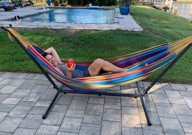 A reviewer is pictured sitting in a hammock by the pool