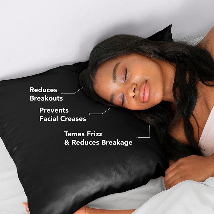 A model lounging on a black satin pillowcase with bullet points highlighting: reduces breakouts, prevents facial creases, tames frizz, and minimizes hair breakage.