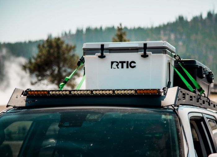 The white cooler placed on top of a car.