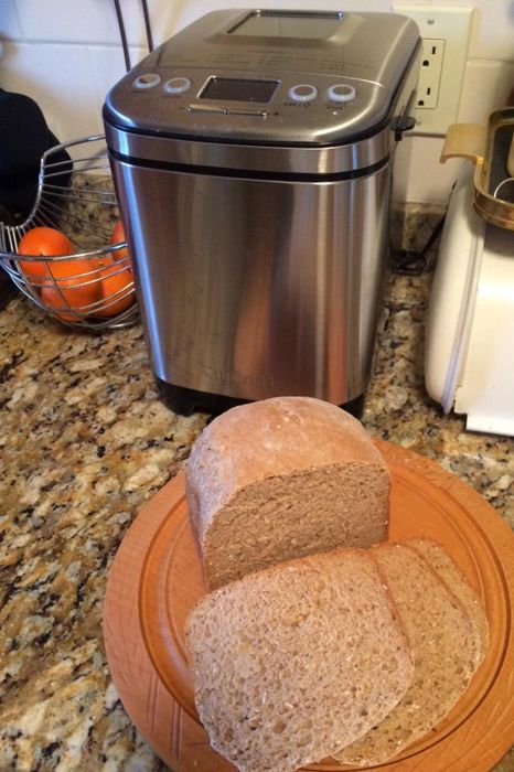 A reviewer image featuring a bread machine on a counter alongside a plate of freshly sliced bread.