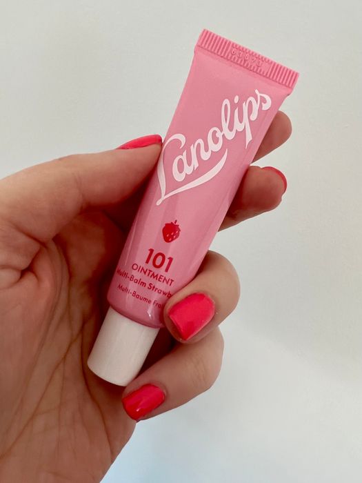 An editor holding a pink tube of Lanolips Multi-Balm in Strawberry