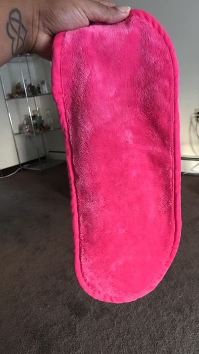 A reviewer holding up the large, pink Makeup Eraser, ready to remove makeup with ease.