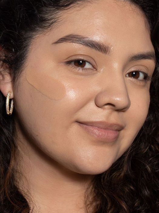 A model showing off a swatch of the tint on their cheek, showcasing its smooth texture.