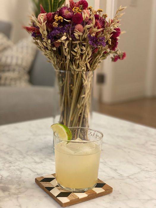 A margarita garnished with a lime wedge, freshly made by the Bartesian.