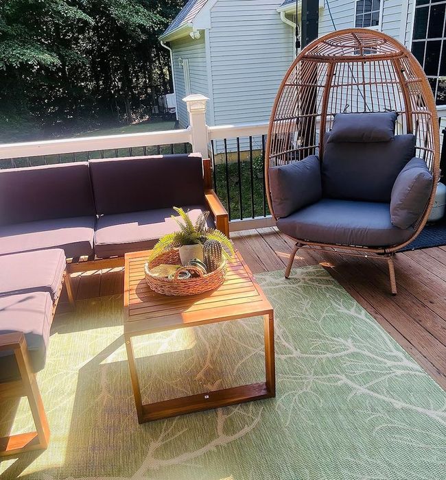 An outdoor furniture arrangement including a sofa, table, egg chair, and decorative accents on a patio, offering great inspiration for home shopping