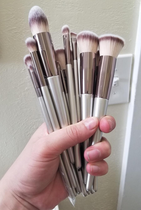 A reviewer holding a collection of makeup brushes of different sizes