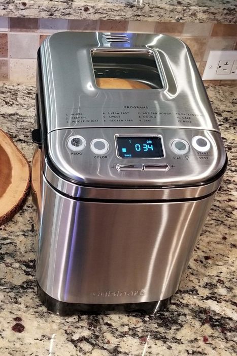 A bread maker resting on the counter, with a loaf visible through the clear window on the lid.