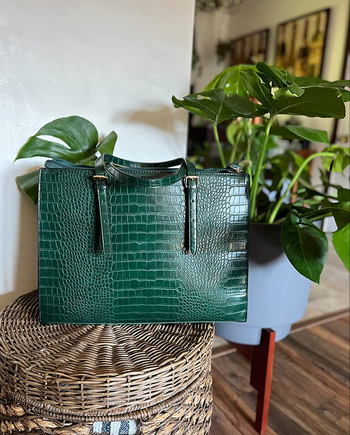 A stylish green faux snakeskin handbag with sleek handles
