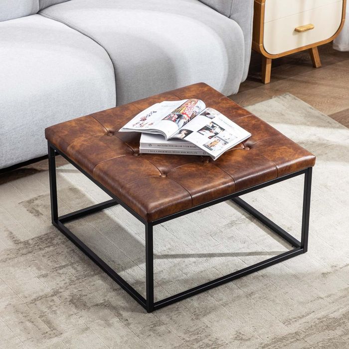 A leather-upholstered ottoman with a black metal base