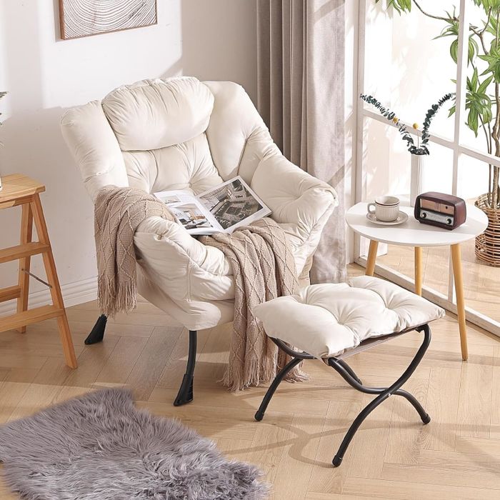 A cozy armchair and ottoman combination, complete with a throw blanket and magazine, creating a perfect, well-lit reading nook.