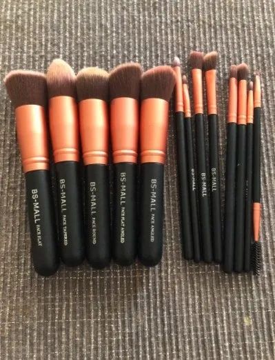 A neatly arranged set of makeup brushes laid out on a rug