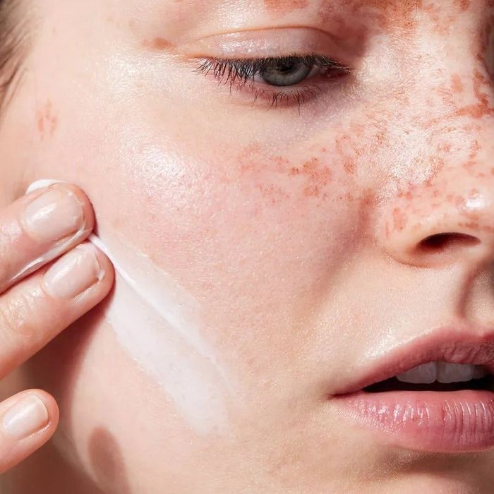 Close-up of a person gently applying the cream to their skin