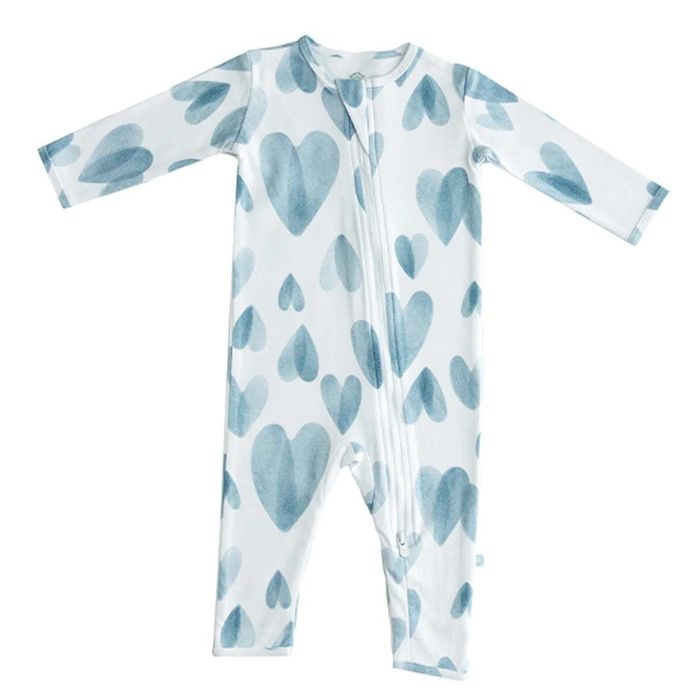 White zip-up baby pajamas with blue hearts scattered across the fabric
