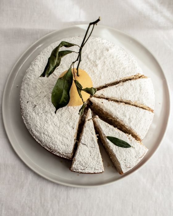 a top view of a cake dusted with powdered sugar and adorned with a slice of lemon on top