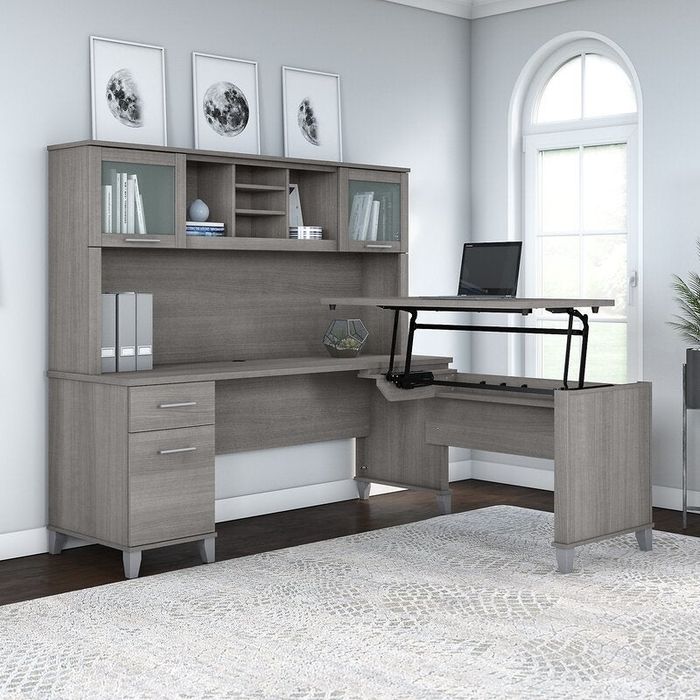 L-shaped desk with a hutch, shelves, and drawers in a home office setting, featuring a laptop on a raised stand and a patterned rug on the floor