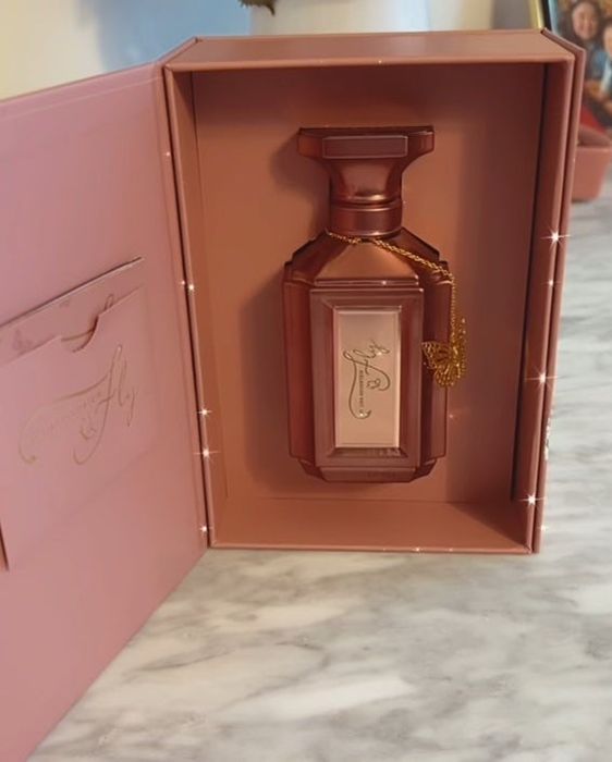 A rose gold perfume bottle with a butterfly charm