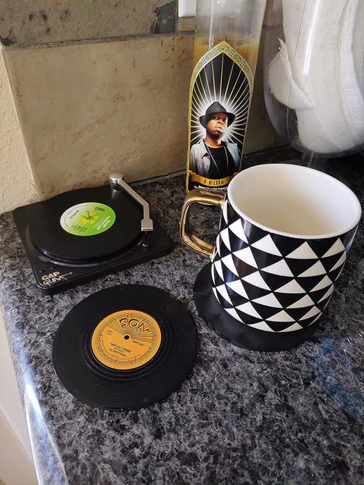 A reviewer’s mug resting on a coaster, with several coasters placed inside a miniature record player.