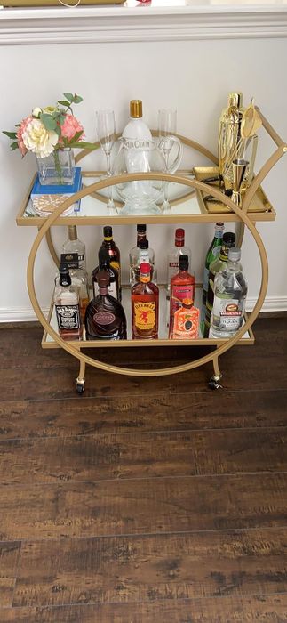 reviewer's bar cart featuring a gold frame, stocked with liquor and glasses