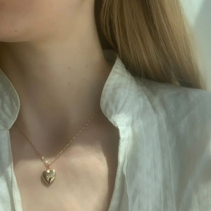 A heart-shaped locket worn by a model, showcasing its delicate design.