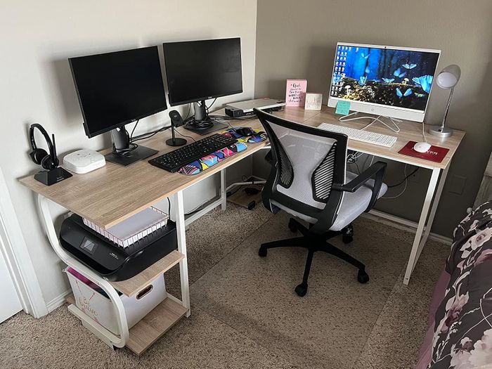 A reviewer's white L-shaped desk with shelves that hold a printer and a box