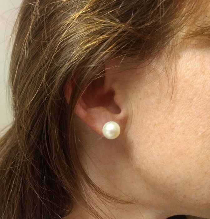A reviewer showcasing a large pearl earring.