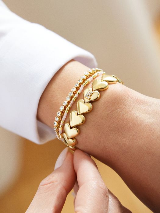 A stretchy gold bracelet with heart charms and a personalized initial.