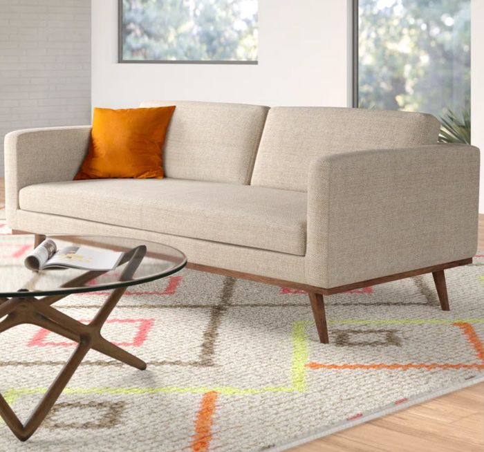 beige upholstered sofa with a wooden base and sleek legs, offering a clean and modern look