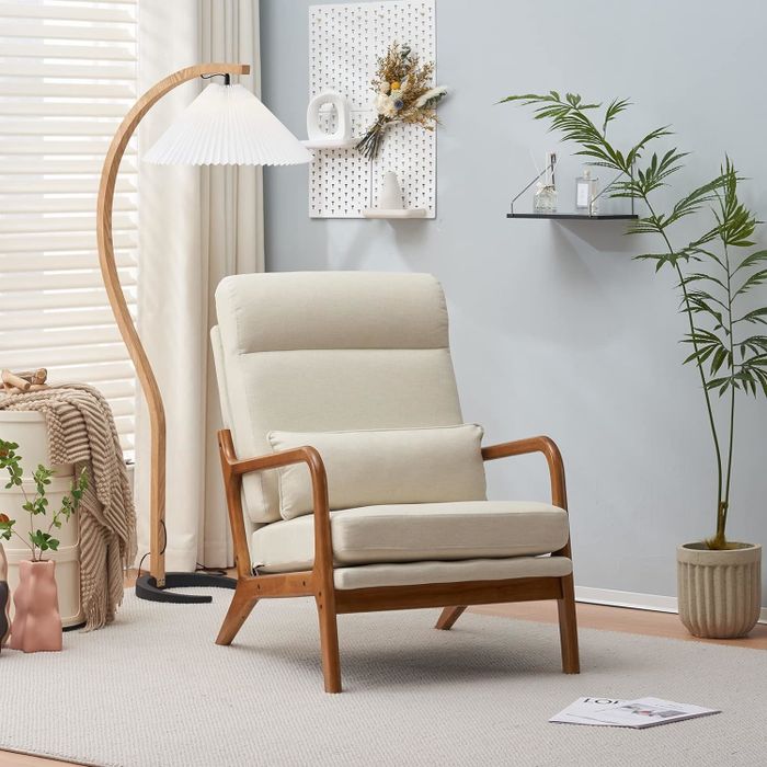 A modern armchair featuring a wooden frame and cream upholstery, placed in a cozy room setting