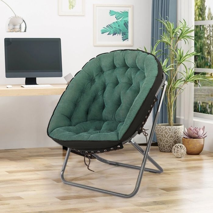 A plush green circular chair resting on a metal frame, perfectly situated in a sleek, minimalist home office that includes a desk, computer, and some plants.