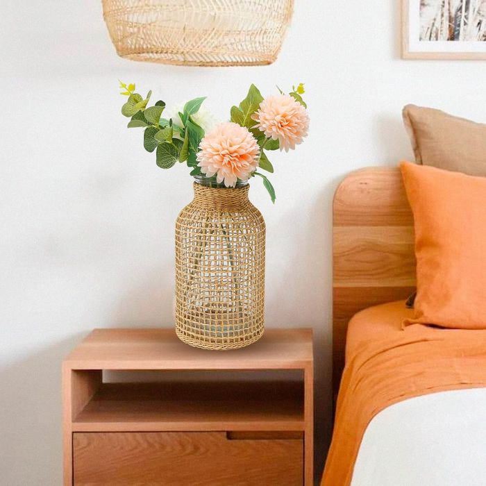 A modern, minimalist bedroom featuring a nightstand with a wicker vase holding flowers placed beside the bed
