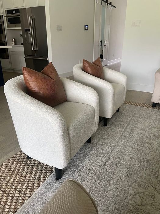 a pair of bouclé fabric chairs with brown cushions in a modern living room setup