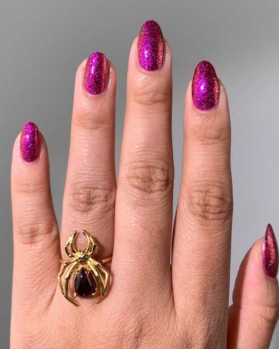 A model flaunting vibrant purple/pink glitter nails.