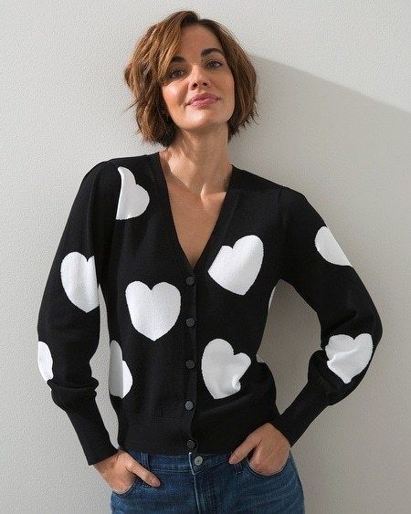 A model wearing a black button-up cardigan with white heart patterns