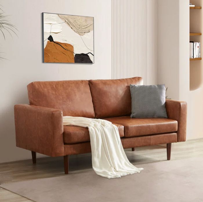 compact faux leather loveseat adorned with a throw blanket and checkered cushion