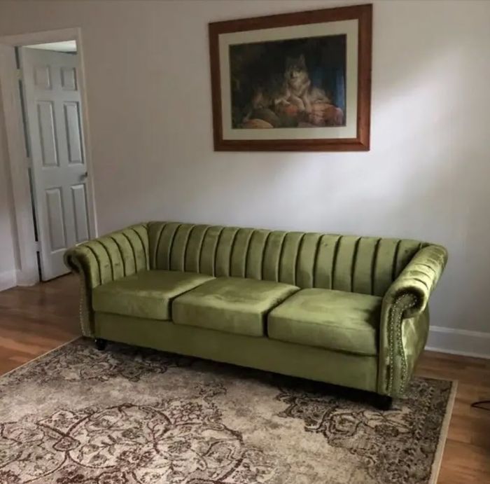 grey velvet sofa featuring elegant curved armrests and a stylish nailhead trim